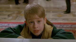 Young Macaulay Culkin as Kevin McCallister wearing a green and yellow coat in Home Alone 2.